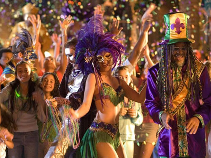 Xandra in a feathered mask dancing in a Mardi Gras street celebration with confetti in the air